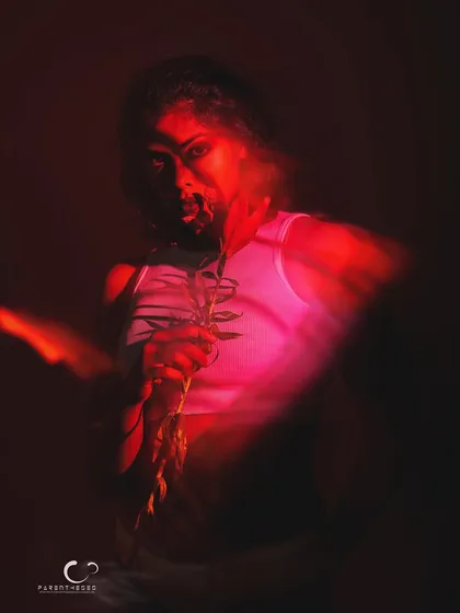 An intense and dramatic portrait where the subject emerges from the blur. The red light creates a fiery, passionate mood, and her gaze is captivating.