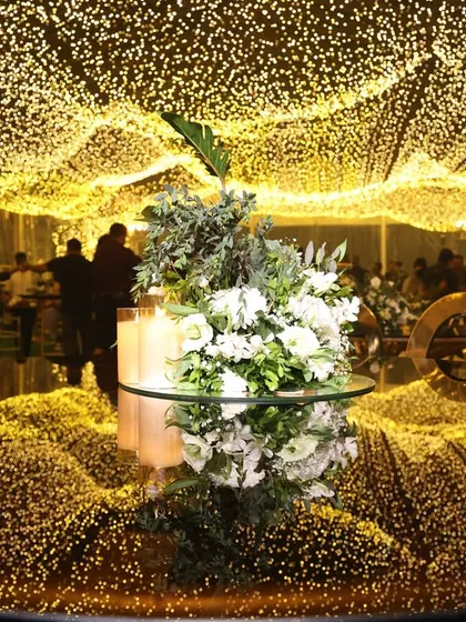 A stunning wedding reception under a ceiling of fairy lights. The unique, undulating table design creates a dynamic and immersive environment for guests.
