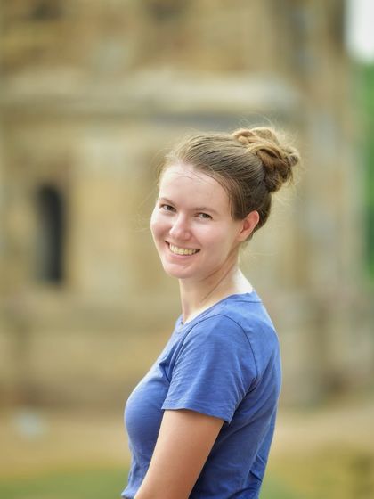 A simple, happy portrait of a tourist enjoying her time in Delhi. Her natural smile and the historic background make for a lovely travel memory.