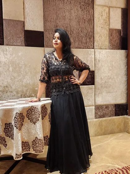 An elegant all-black ensemble featuring a sheer lace top and a flowing skirt. This look is ideal for formal events or festive occasions where sophistication is key.