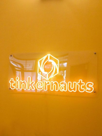 Welcome to the Tinker Den! Our neon sign lights up our creative space in Langford Town, where we're always ready for the next project.