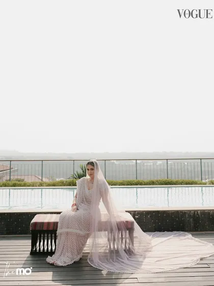 The bride seated by the infinity pool at the Hilton Goa, a beautiful shot from the Vogue wedding feature. Her elegant pose and the expansive view create a sense of calm and luxury.