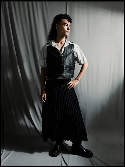 A full-length shot of a model in a gender-fluid outfit. The dramatic lighting and shadows create a powerful, high-contrast image.