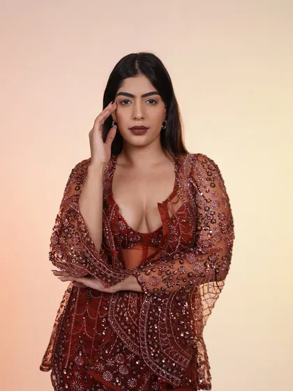 A close-up of the rust-colored Indo-Western outfit, focusing on the confident pose and the intricate details of the ensemble.