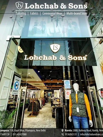 Welcome to Lohchab & Sons. Our modern glass storefront in Delhi invites you into a world of curated style, where you can see a mannequin styled in a casual yellow shirt and a contemporary puffer vest, giving you a taste of the trends inside.