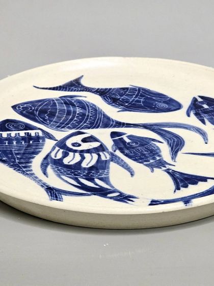 An angled view of my hand-painted ceramic fish plate. The unique patterns on each fish are created to add artistic flair, making it a perfect piece for interior designers and architects looking for unique decor.