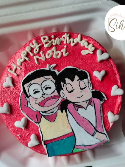 A nostalgic and romantic cake featuring Nobita and Shizuka from Doraemon. This hand-drawn design on a bright red bento is perfect for a fan celebrating a birthday or anniversary.