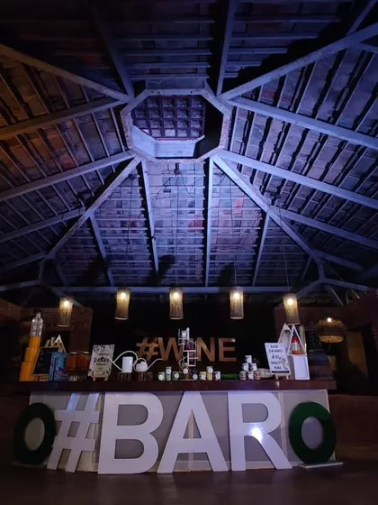 This rustic bar setup was designed to complement the venue's open-air gazebo structure. The large '#BARO' lettering adds a bold, modern touch to the otherwise natural and earthy theme.