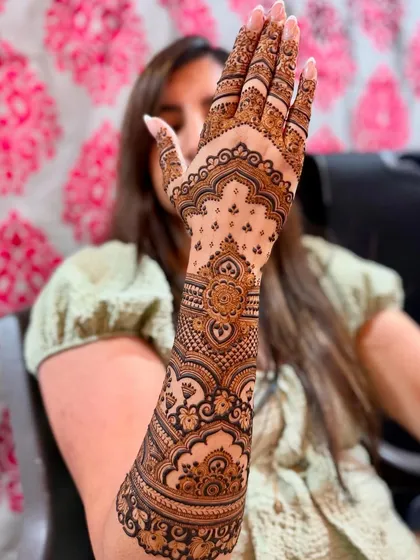 A lovely bride-to-be posing with her full-arm engagement mehendi.