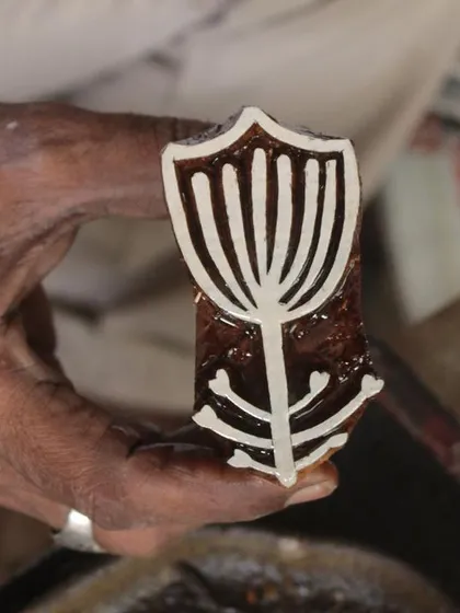 A close-up of a master carver's hands bringing a floral design to life on a teak block. This particular block was created for a collaborative workshop with the Fabric Workshop Museum in Philadelphia.