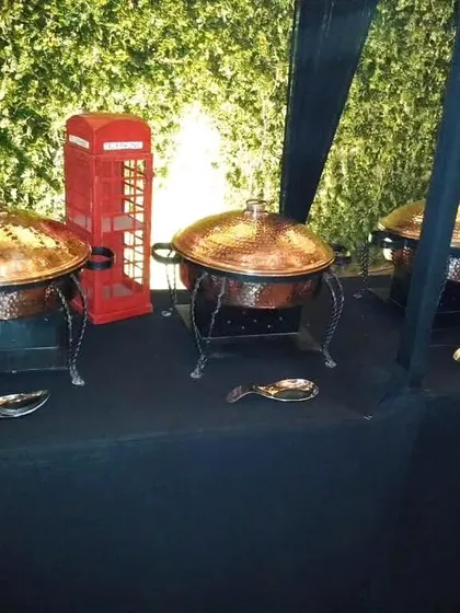 A themed buffet setup featuring a classic red British telephone booth prop alongside our copper chafing dishes, showing how we can customize decor.