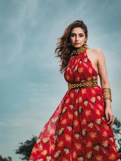 A low-angle shot against a bright blue sky, making the model in her vibrant red dress appear powerful and statuesque. This technique is great for creating heroic and memorable fashion images.
