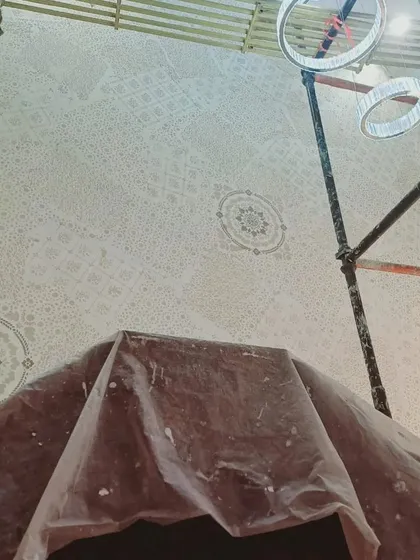 A closer look at the detailed stencil work on a ceiling. Notice how we protect the surrounding areas, like the chandelier, to ensure a clean and professional application. This level of detail is part of our standard process.