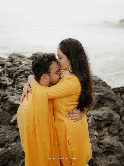 A loving embrace on a rocky shore, this pre-wedding photo captures a moment of quiet connection against the vastness of the sea.