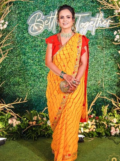 A vibrant and fun party makeup look. The client's bright yellow saree is complemented by fresh, glowing makeup that makes her look ready to celebrate.