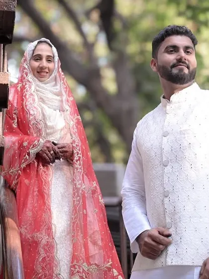 A candid moment between a bride and groom, sharing a smile during their outdoor Nikkah ceremony. The natural setting adds a fresh and relaxed feel to this traditional Muslim wedding portrait.