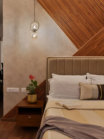 The details are what elevate a good design to a great one. This close-up shot highlights the interplay of textures in a bedroom we designed, from the geometric wood-paneled headboard and soft-textured wall to the warm glow of the pendant light.
