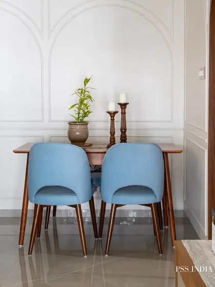 Simple elegance defines this dining nook. Light blue upholstered chairs add a soft pop of color against the white wall with classic arch moldings, creating a fresh and inviting space.