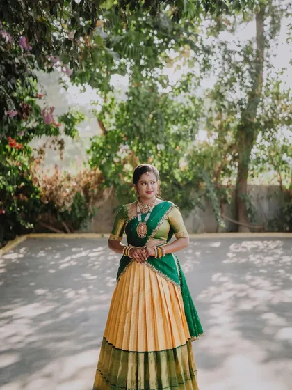 The Langa Voni, or half saree, is a timeless expression of South Indian grace. This piece, in shades of mango yellow and deep green, was designed with a pleated Kanchipuram silk skirt for a classic yet comfortable silhouette.