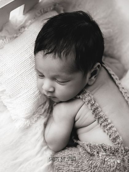 A classic pose for a baby boy, dressed in a simple knit overall. This timeless look focuses on his sweet, sleepy form.