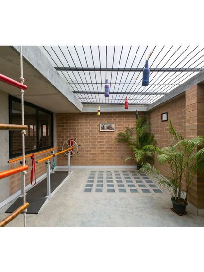 This covered outdoor therapy and play area allows children to engage in physical activities in a safe, naturally ventilated space. The use of simple, durable materials like brick and concrete ensures longevity.