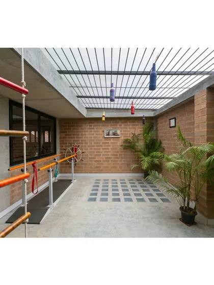 This covered outdoor therapy and play area allows children to engage in physical activities in a safe, naturally ventilated space. The use of simple, durable materials like brick and concrete ensures longevity.