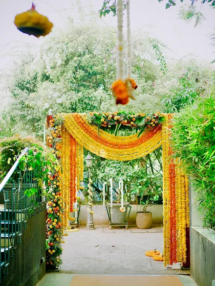 An inviting entrance arch for a Haldi celebration, heavily adorned with cascading garlands of yellow and orange marigolds. This floral archway sets a festive tone right from the moment guests arrive.