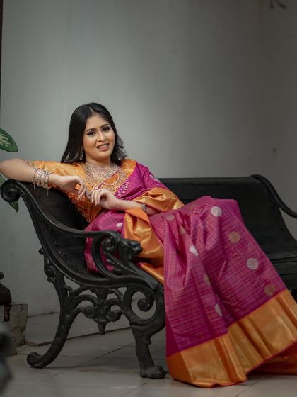 A moment of regal repose, the model seated on a bench, the rich silk of her saree spread out around her.
