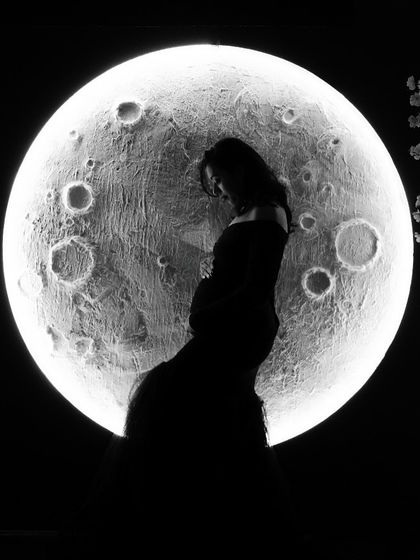 A moody and artistic silhouette in front of our moon prop. This black and white image creates a sense of mystery and wonder, highlighting the beautiful curve of the baby bump.