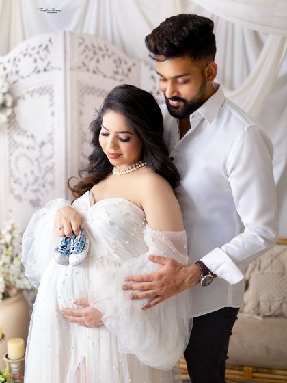 A close-up look at the details, with the couple holding a tiny pair of baby shoes. It’s a sweet way to symbolize the little one on the way.