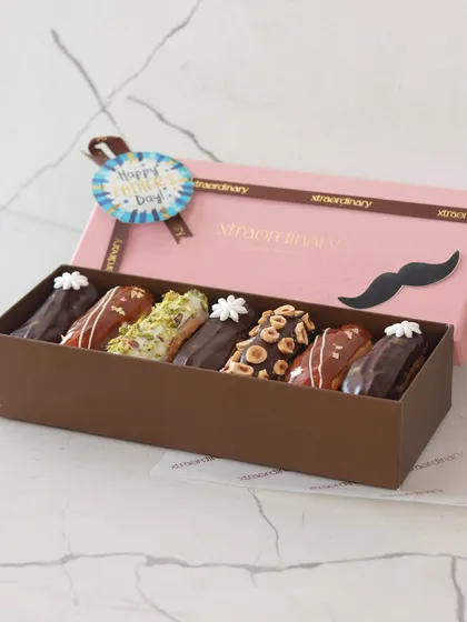 A box of our assorted gourmet eclairs, specially packaged for Father's Day with a "Happy Father's Day" tag and a cute mustache detail.