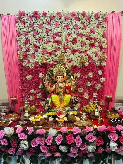 A beautiful wall of pink and white roses provides a classic and elegant backdrop for this Ganpati celebration. The decor extends to the base, creating a complete and cohesive floral look.