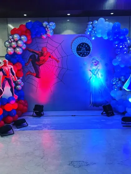 A fun crossover theme combining Spider-Man and Frozen for a 5th birthday. The backdrop is split with red and blue lighting to represent both characters, complete with balloon garlands and a marquee number.