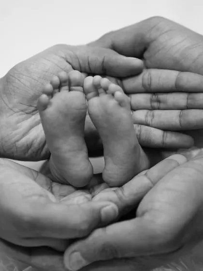 The tiniest feet make the biggest footprints in our hearts. This classic black and white shot of a newborn's feet held in their parents' hands is a timeless keepsake.
