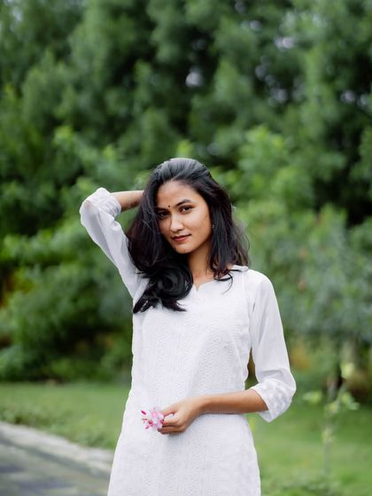 A simple and elegant portrait in a white kurta. The natural green background makes the white outfit pop, creating a fresh and serene image.