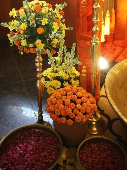 Detail of the floral arrangements for a Haldi ceremony. I combine marigolds with yellow roses and tuberoses in brass stands, alongside bowls of fresh rose petals for the rituals.
