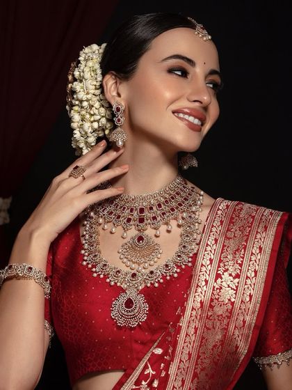 Timeless elegance for an evening function. This bride's classic red saree is paired with a radiant makeup look, a traditional floral bun, and stunning jewelry, creating a look that is both graceful and glamorous.