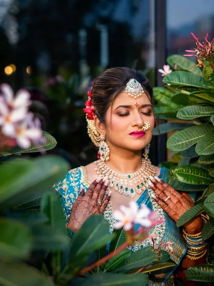 A peaceful portrait of the bride amidst flowers. Her eyes are closed, highlighting the beautiful eye makeup and her serene expression.