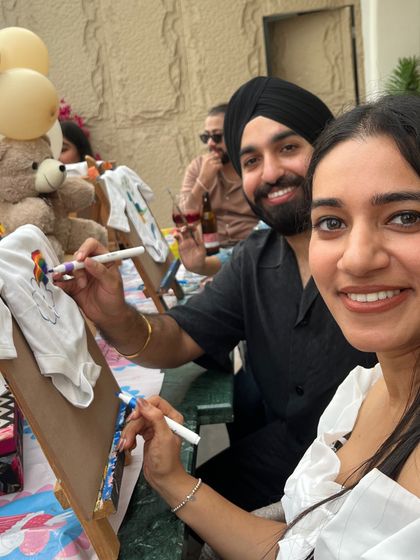 This couple is adding their artistic touch to a baby onesie. It's a fun way for all guests to contribute a personal gift.